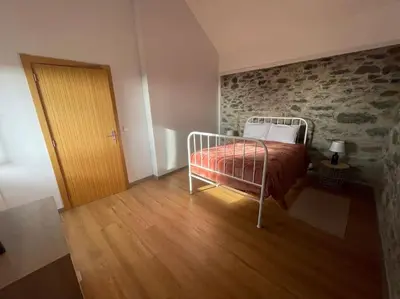 a bedroom with a bed and a stone wall at Casa Rustica da Maloeira in Fajã da Ovelha