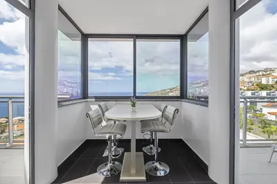 a table and chairs in a room with large windows at Cote D Atlantique by Homie in Caniço
