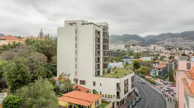 a tall white building in a city with a street at The Suite QM in Funchal