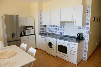 a kitchen with white cabinets and a washer and dryer at Bela Vista Capazi in Porto Santo
