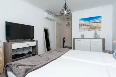 a white bedroom with a large bed and a flat screen tv at Villa Liana by LovelyStay in Ponta do Sol