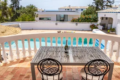 a table and chairs on a balcony with a swimming pool at Casa Azul in Luz