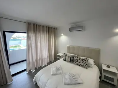 a bedroom with a bed and a large window at Apartamento Don Tenório com piscina Sagres in Sagres