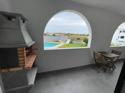 a kitchen with an arched window and a table and chair at Apartamento Don Tenório com piscina Sagres in Sagres