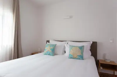 a bedroom with a bed with white sheets and pillows at Casa da praia in Carrapateira