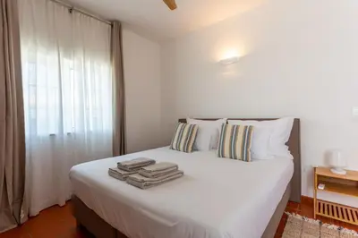 a bedroom with a white bed with towels on it at Casa da praia in Carrapateira