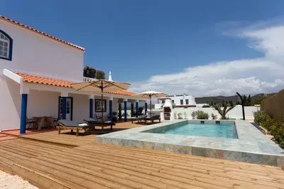 a backyard with a swimming pool and a wooden deck at Casa da praia in Carrapateira