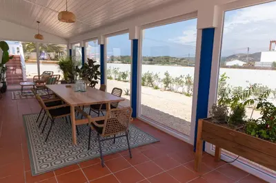 a porch with a wooden table and chairs and windows at Casa da praia in Carrapateira