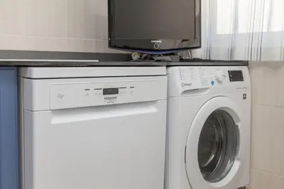 a tv on a counter above a washing machine at C22 - Beco do Poço Beach Townhouse in Praia da Luz in Luz