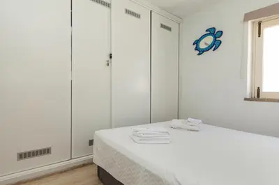 a white room with a bed and white wardrobes at C22 - Beco do Poço Beach Townhouse in Praia da Luz in Luz