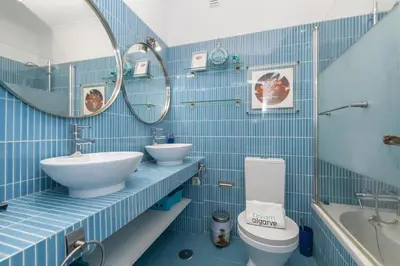 a blue tiled bathroom with a toilet and a sink at C22 - Beco do Poço Beach Townhouse in Praia da Luz in Luz