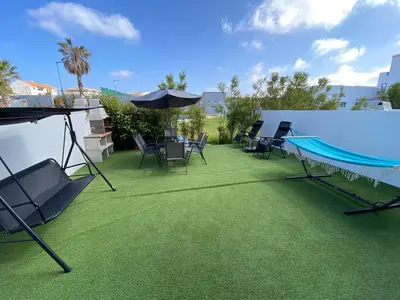 a patio with chairs and a pool and an umbrella at Casa com terraço e piscina Sagres in Sagres