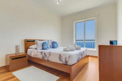a bedroom with a bed with a large window at Sunset Horizon by Atlantic Holiday in Estreito de Câmara de Lobos