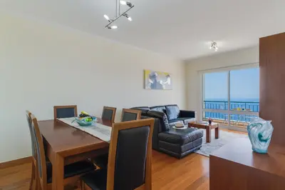 a living room with a dining room table and a couch at Sunset Horizon by Atlantic Holiday in Estreito de Câmara de Lobos