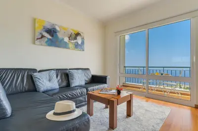 a living room with a couch and a large window at Sunset Horizon by Atlantic Holiday in Estreito de Câmara de Lobos