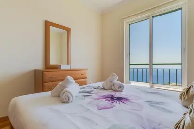 a bedroom with a bed with towels and a window at Sunset Horizon by Atlantic Holiday in Estreito de Câmara de Lobos