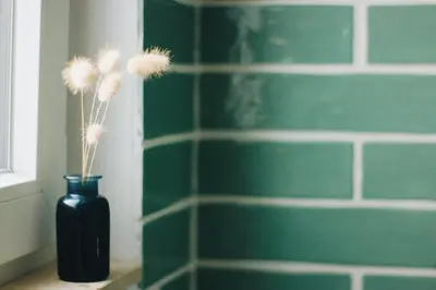 a black vase with dried flowers in a bathroom at Little Bispo Apartments in Vila do Bispo