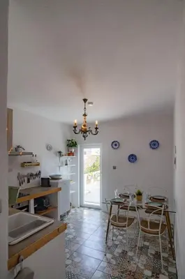 a kitchen with a table and chairs and a chandelier at Little Bispo Apartments in Vila do Bispo