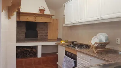 a kitchen with a stove top oven next to a fireplace at Casa Luciana in Ponta do Pargo