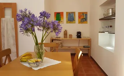 a vase with purple flowers on a wooden table at Casa Luciana in Ponta do Pargo