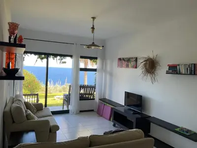 a living room with a couch and a television and the ocean at Sea to see - sea front view in Caniço