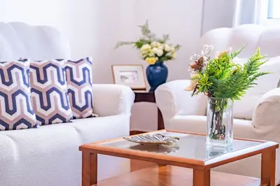 a living room with two chairs and a vase with flowers on a table at Villa Bella Mar by Homie in Porto Santo