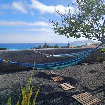 a blue hammock sitting on the ground near the ocean at Villa Bella Mar by Homie in Porto Santo
