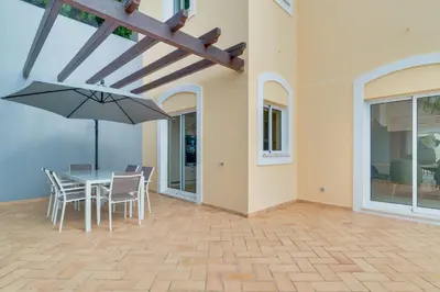 a patio with a table and chairs and an umbrella at Villa Gasparini Palheiro Village by Holiday Rental Madeira in Funchal