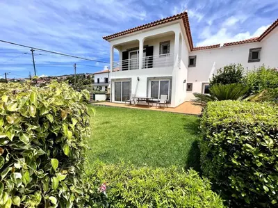 a large white house with a green yard at Casa Darcey by Your Madeira Rentals in Estreito da Calheta