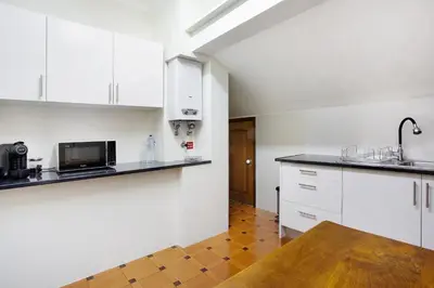 a kitchen with white cabinets and a wooden floor at Penthouse Vista Mar in Funchal