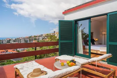 a room with a balcony with a bed and a table at Matur I by An Island Apart in Água de Pena
