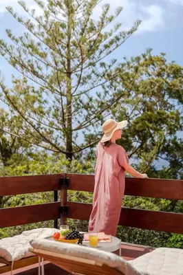 a woman in a hat standing on a fence at Matur I by An Island Apart in Água de Pena