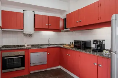 a red kitchen with red cabinets and appliances at Matur I by An Island Apart in Água de Pena