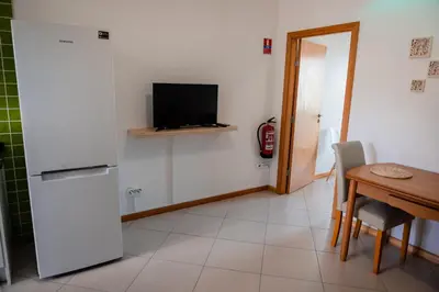 a kitchen with a refrigerator and a table and a television at Villas Horizonte Capazi in Porto Santo
