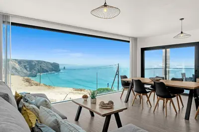 a living room with a table and a view of the ocean at Apartamentos praia da Arrifana in Aljezur