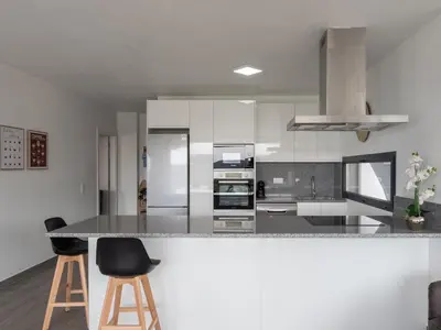 a kitchen with white cabinets and a counter with stools at Apartamentos praia da Arrifana in Aljezur
