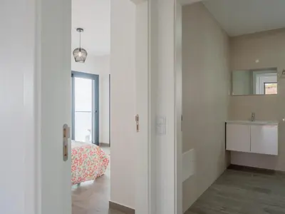 a white room with a bed and a kitchen at Apartamentos praia da Arrifana in Aljezur