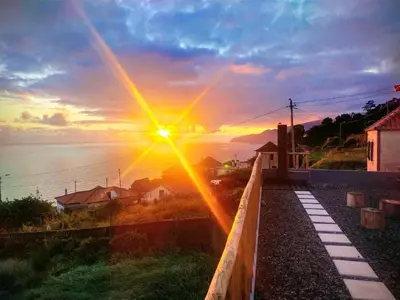a sunset over the ocean with a beam of light at Casa da Ribeira da Janela in Porto Moniz