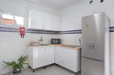 a kitchen with white cabinets and a refrigerator at Casa da Ribeira da Janela in Porto Moniz
