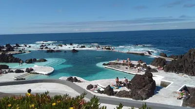 a group of rocks on a beach with the ocean at Casa da Ribeira da Janela in Porto Moniz