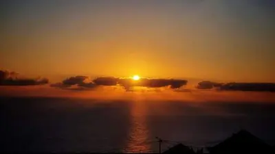 a sunset over the ocean with the sun hiding behind clouds at Casa da Ribeira da Janela in Porto Moniz