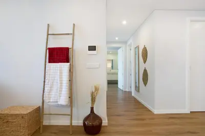 a white hallway with a vase on the floor and a hallway with a stair at Casa Castanheta in Câmara de Lobos
