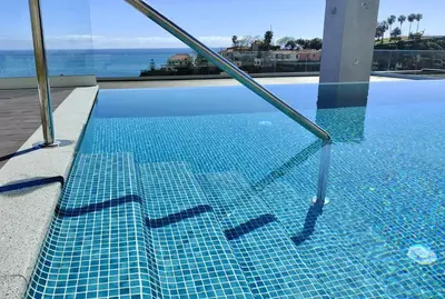 a swimming pool with a blue tiled floor at Casa Castanheta in Câmara de Lobos
