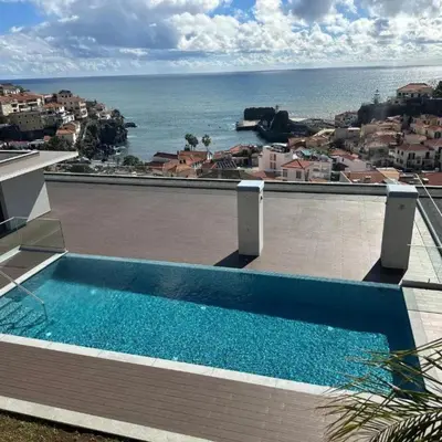 a swimming pool on top of a building with the ocean at Casa Castanheta in Câmara de Lobos