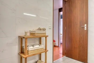 a bathroom with a wooden door and a shelf with towels at Monumental Tower, a Home in Madeira in Funchal