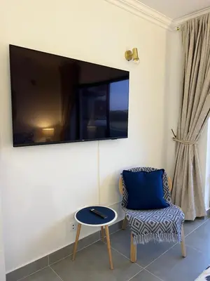 a living room with a chair and a tv on the wall at Retiro do Sossego in Sagres