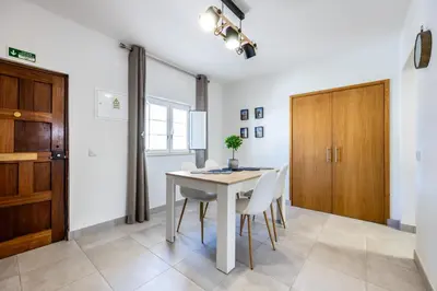 a dining room with a table and chairs and a wooden door at Casa Memória in Vila do Bispo