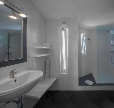 a white bathroom with a sink and a shower at Charmingly furnished Studio with pool in Luz in Luz