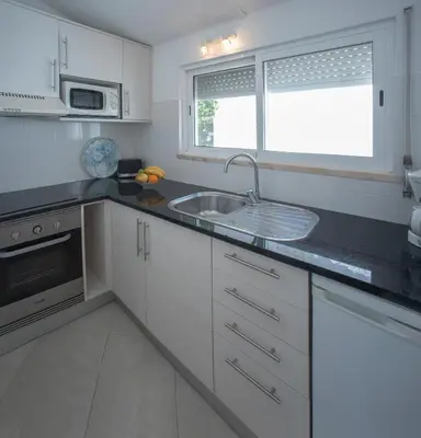 a kitchen with white cabinets and a sink and a window at Charmingly furnished Studio with pool in Luz in Luz