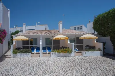 a house with chairs and umbrellas in front of it at Charmingly furnished Studio with pool in Luz in Luz